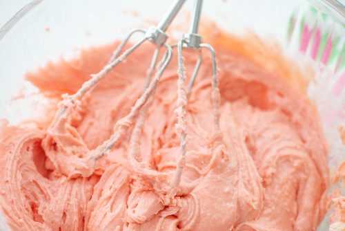 pink cake mix batter in glass bowl.