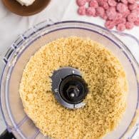 A top down view of a food processor containing sugar cookies that has been processed into crumbs.