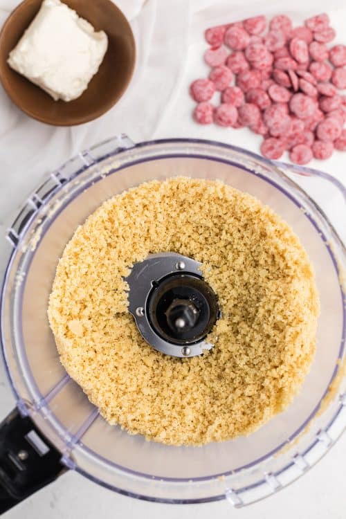 A top down view of a food processor containing sugar cookies that has been processed into crumbs.