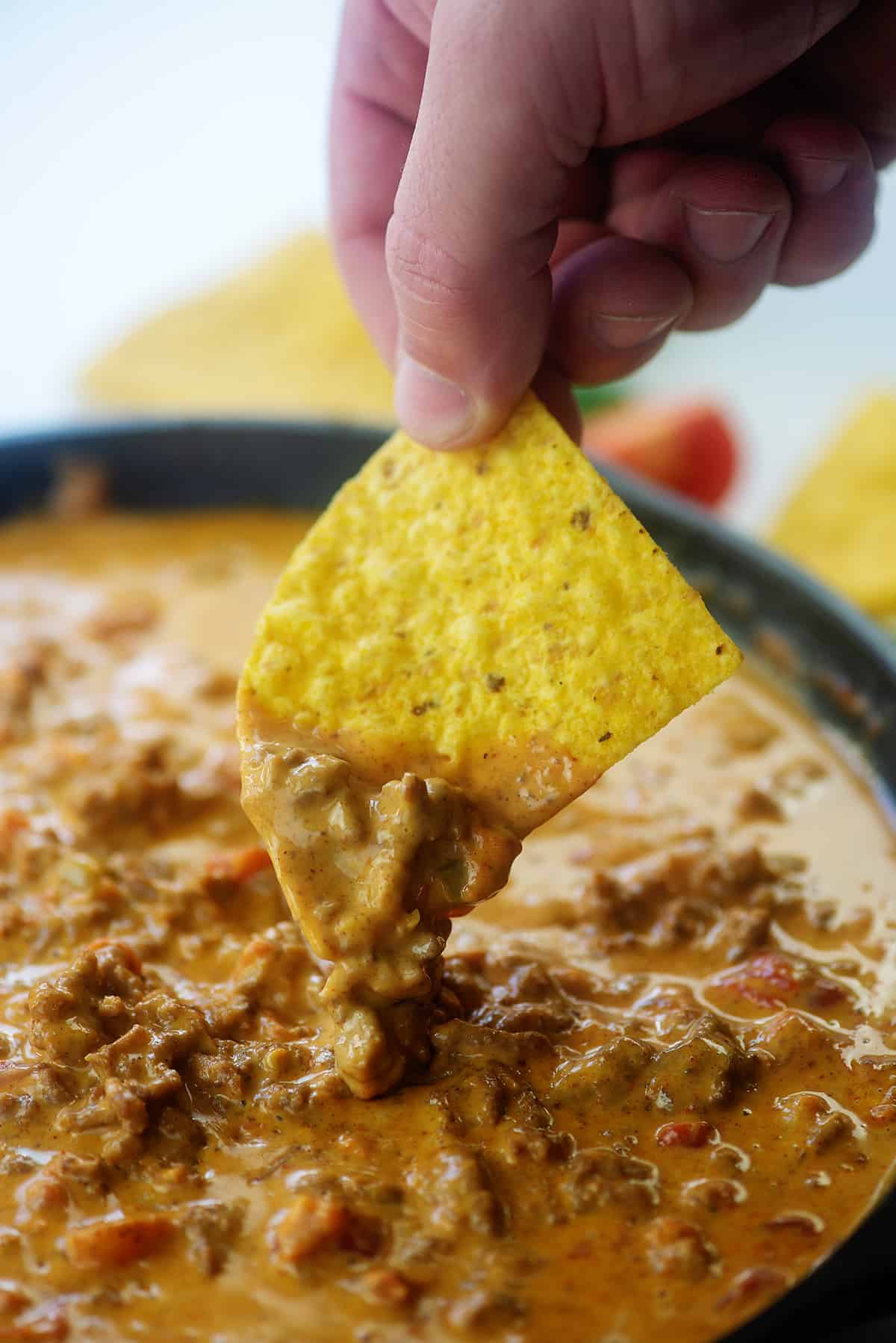 a person dipping a chip into rotel dip.