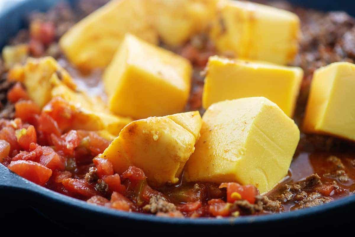 chunks of Velveeta in a skillet with Rotel and ground beef.