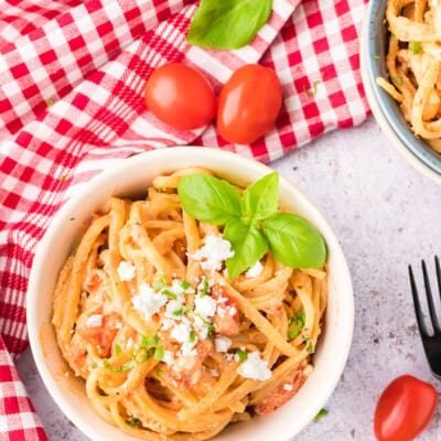 feta pasta in white bowl topped with extra feta crumbles.