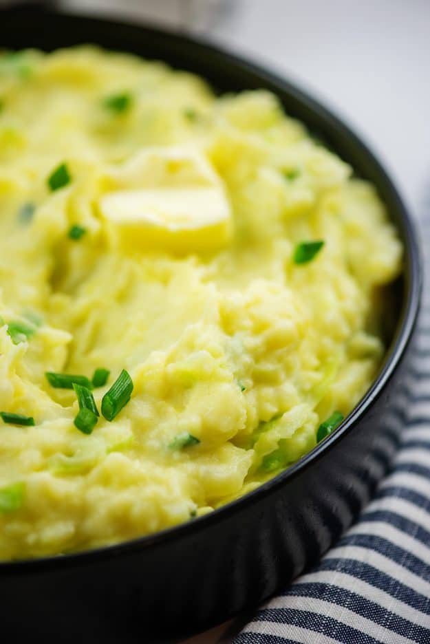 mashed potatoes and cabbage in black serving bowl.