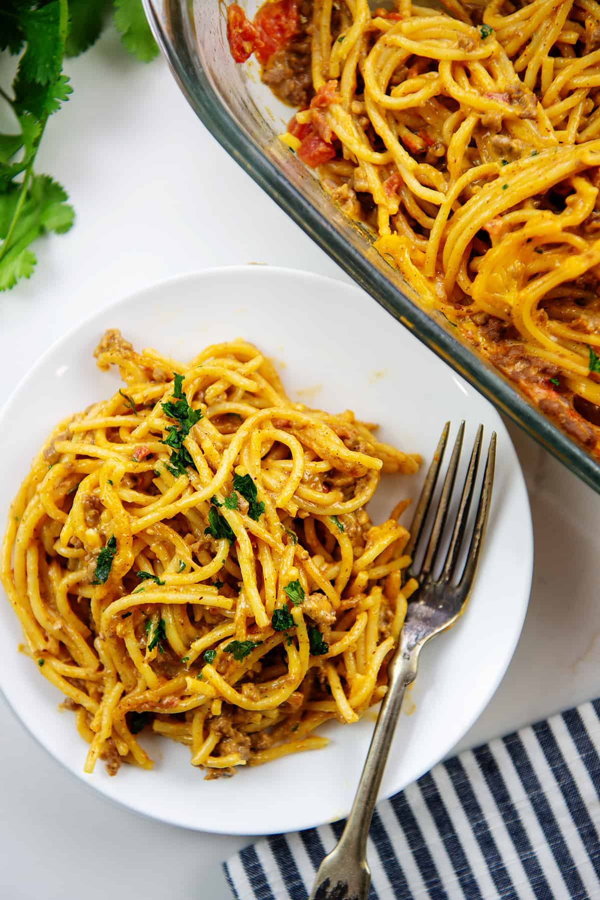 cheesy taco spaghetti bake on white plate.