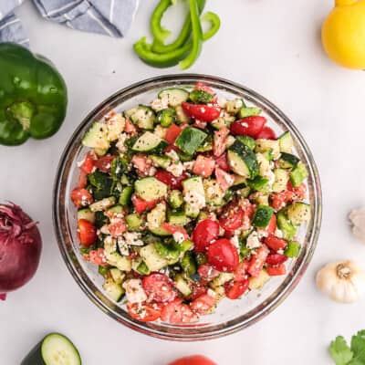 vegetable salad in glass bowl surrounded by fresh veggies.