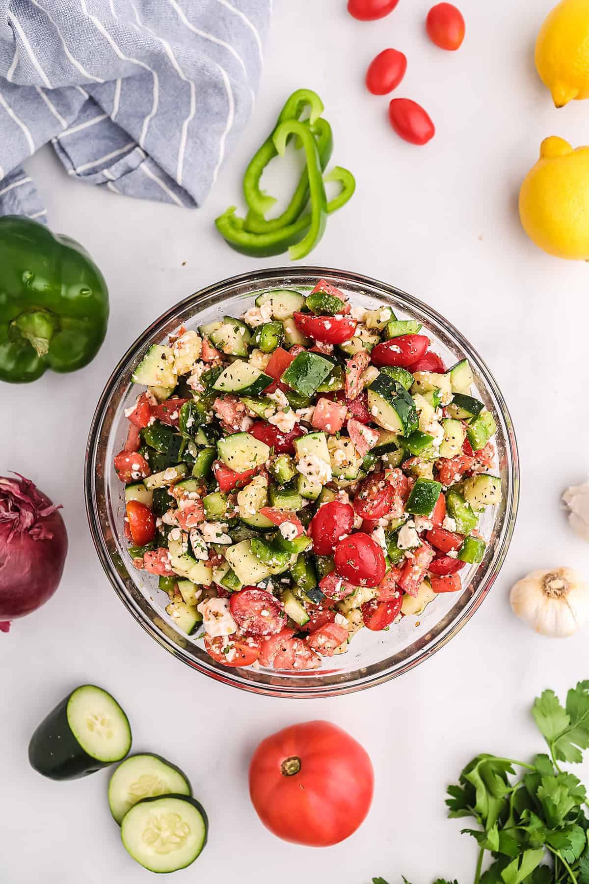 vegetable salad in glass bowl surrounded by fresh veggies.