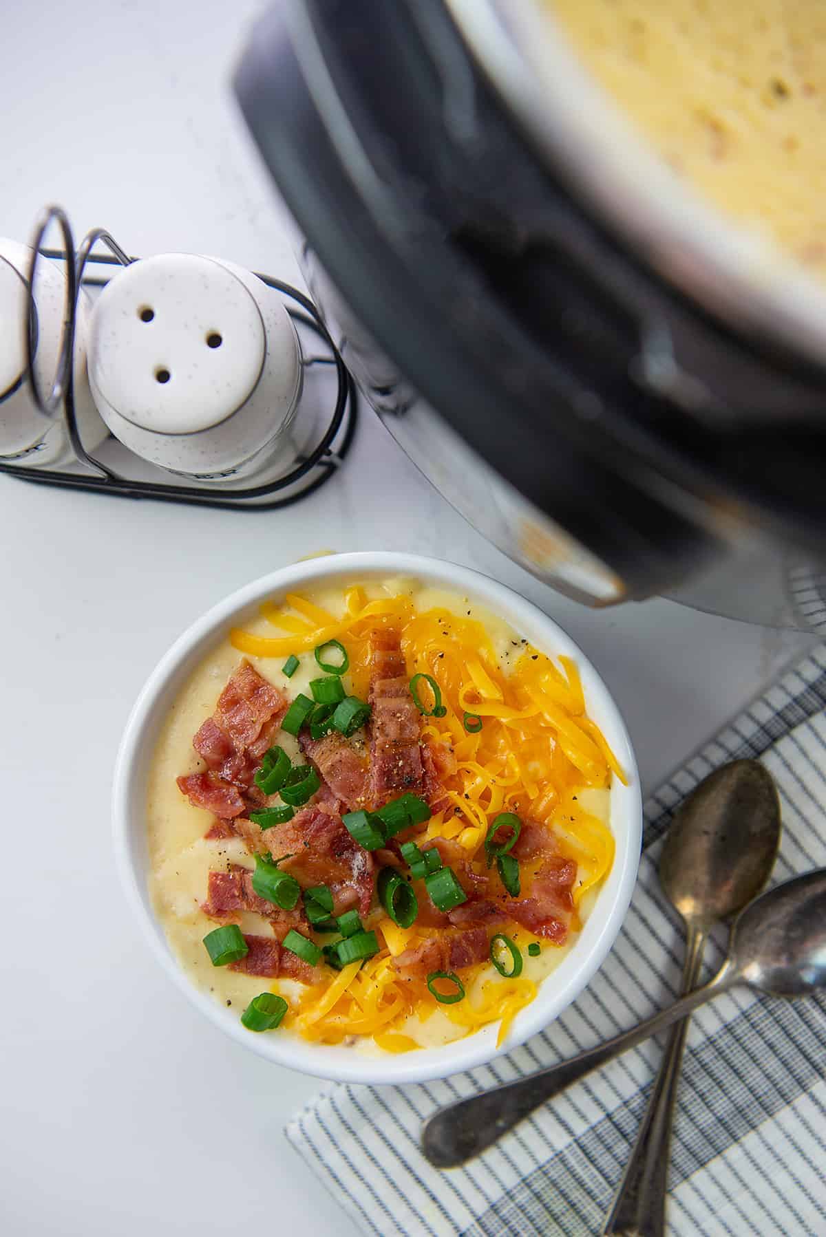 overhead view of potato soup in a bowl next to an Instant Pot.