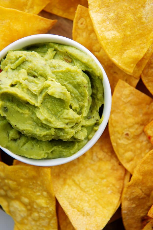 overhead view of air fryer tortilla chips next to a bowl of guacamole.