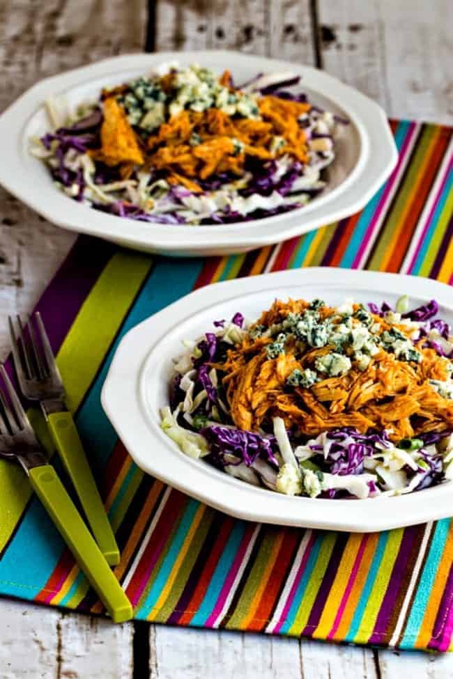 Two bowls of buffalo chicken cabbage on a table next to forks.