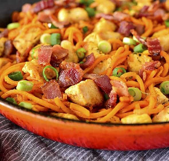 Close up view of buffalo chicken bacon and sweet potato noodles in a skillet.