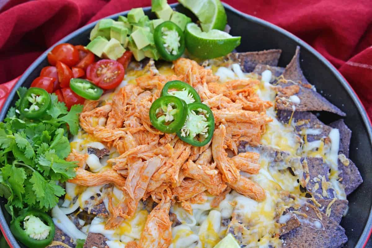 Buffalo chicken nachos with blue corn chips in a bowl.