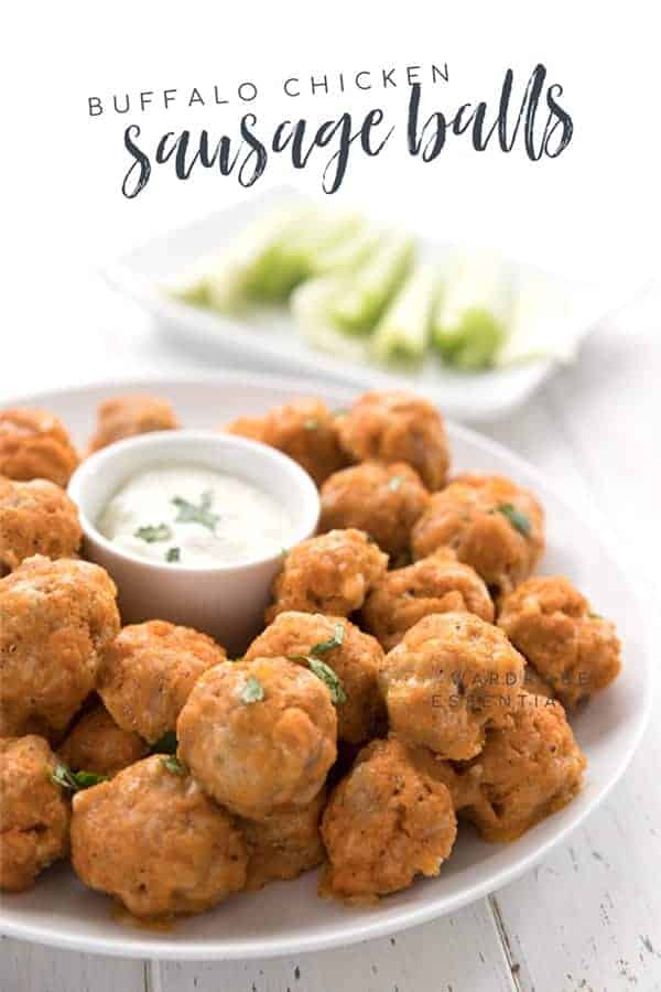 Keto buffalo chicken sausage balls piled on a plate surrounding a small bowl of dip in the center.
