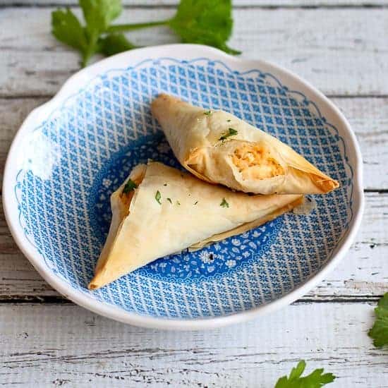 Buffalo chicken phyllo turnovers on a decorative blue and white plate.