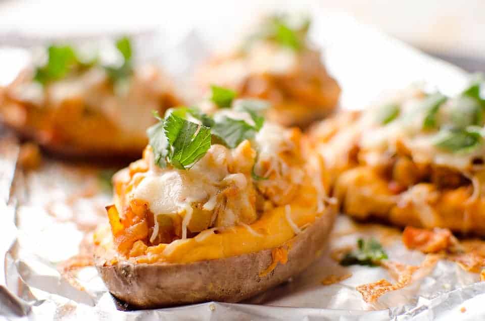 Close up view of twice baked buffalo chicken sweet potatoes cooling on foil.