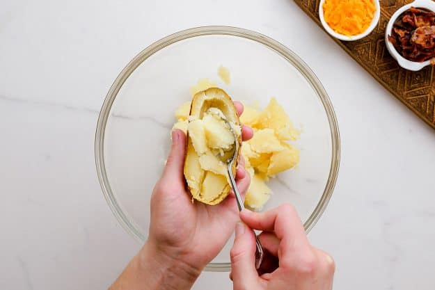 a hand scooping potatoes out of the shell.