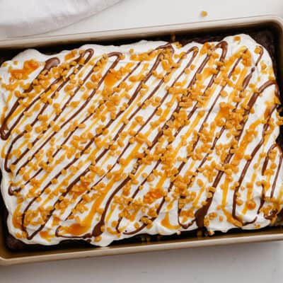 Chocolate cake topped with whipped cream and drizzled with caramel and chocolate.