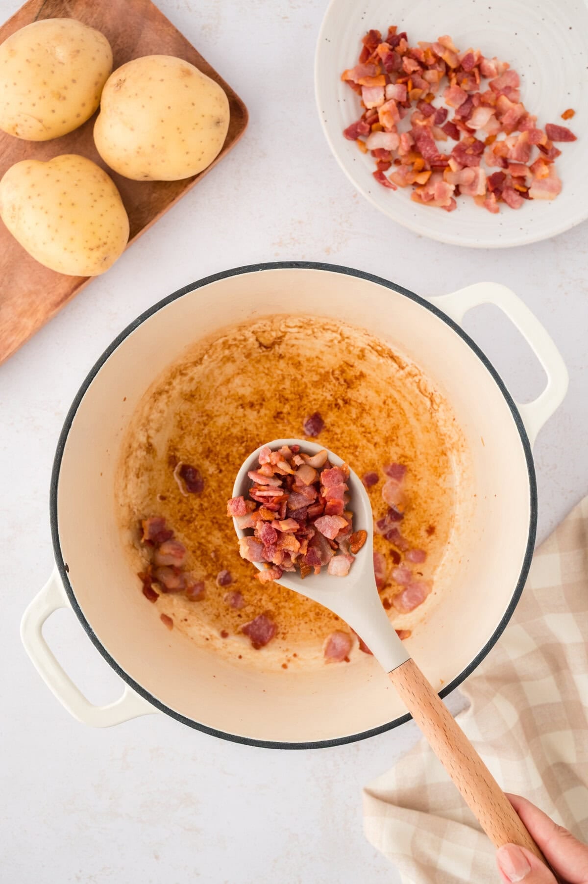 Bacon being removed from dutch oven.