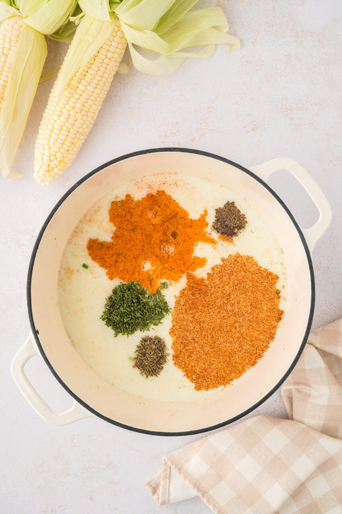 Potatoes and seasoning in pot of soup.