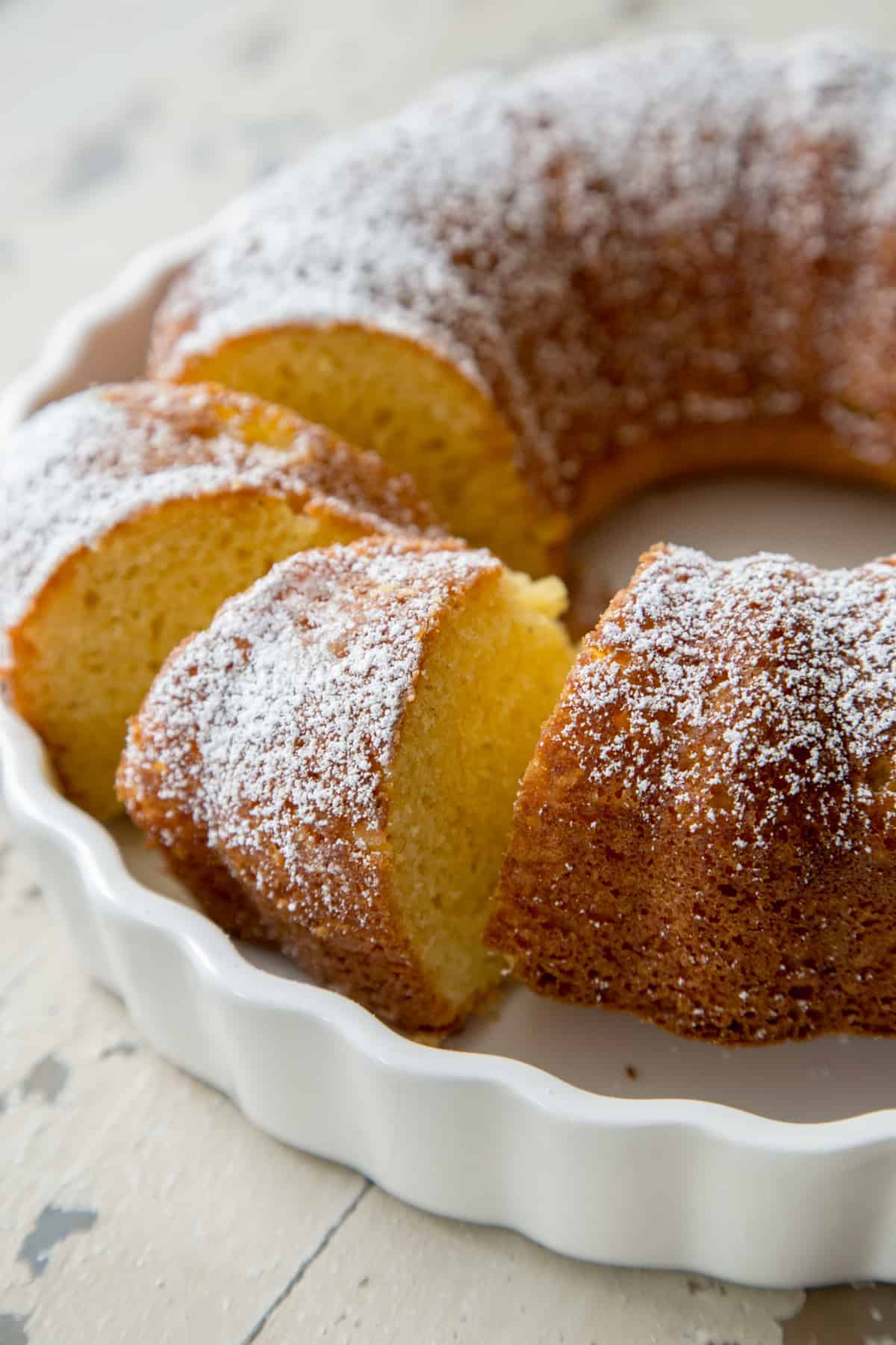 An eggnog Bundt cake in a white dish with two slices cut out of the cake.