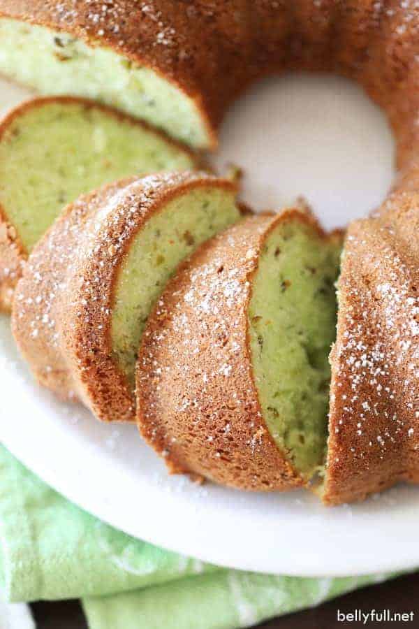 A top down view of a pistachio Bundt cake on a white plate with three cut slices.