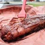 basting ribs on peach butcher paper.