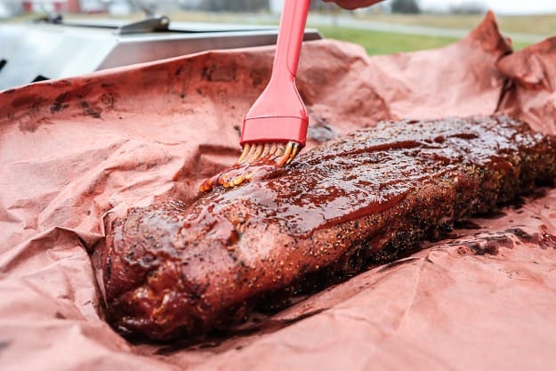 basting ribs on peach butcher paper.