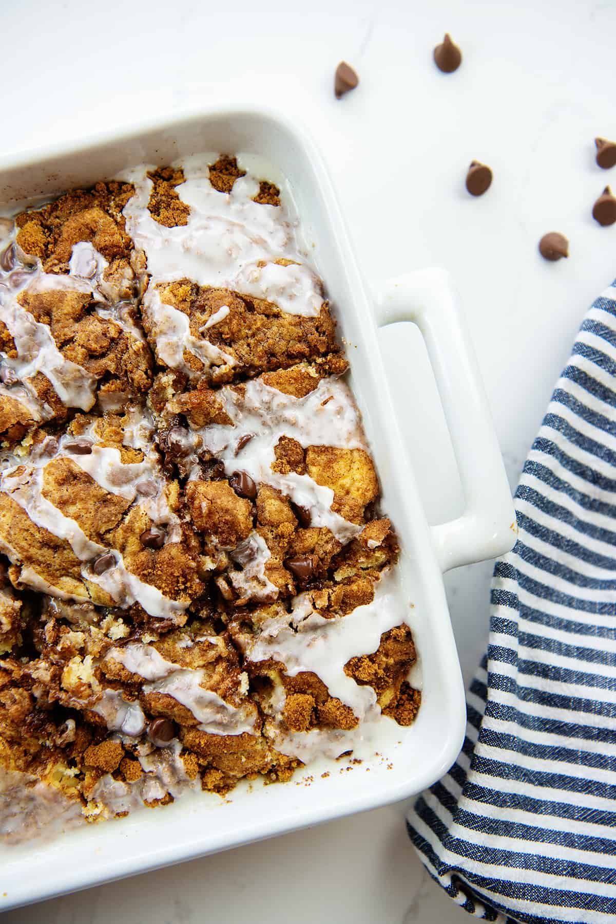 overhead shot of chocolate chip cinnamon roll cake in white dish.