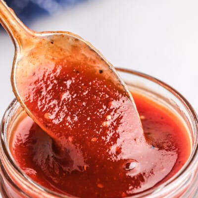 bourbon bbq sauce dripping off a spoon into a mason jar.
