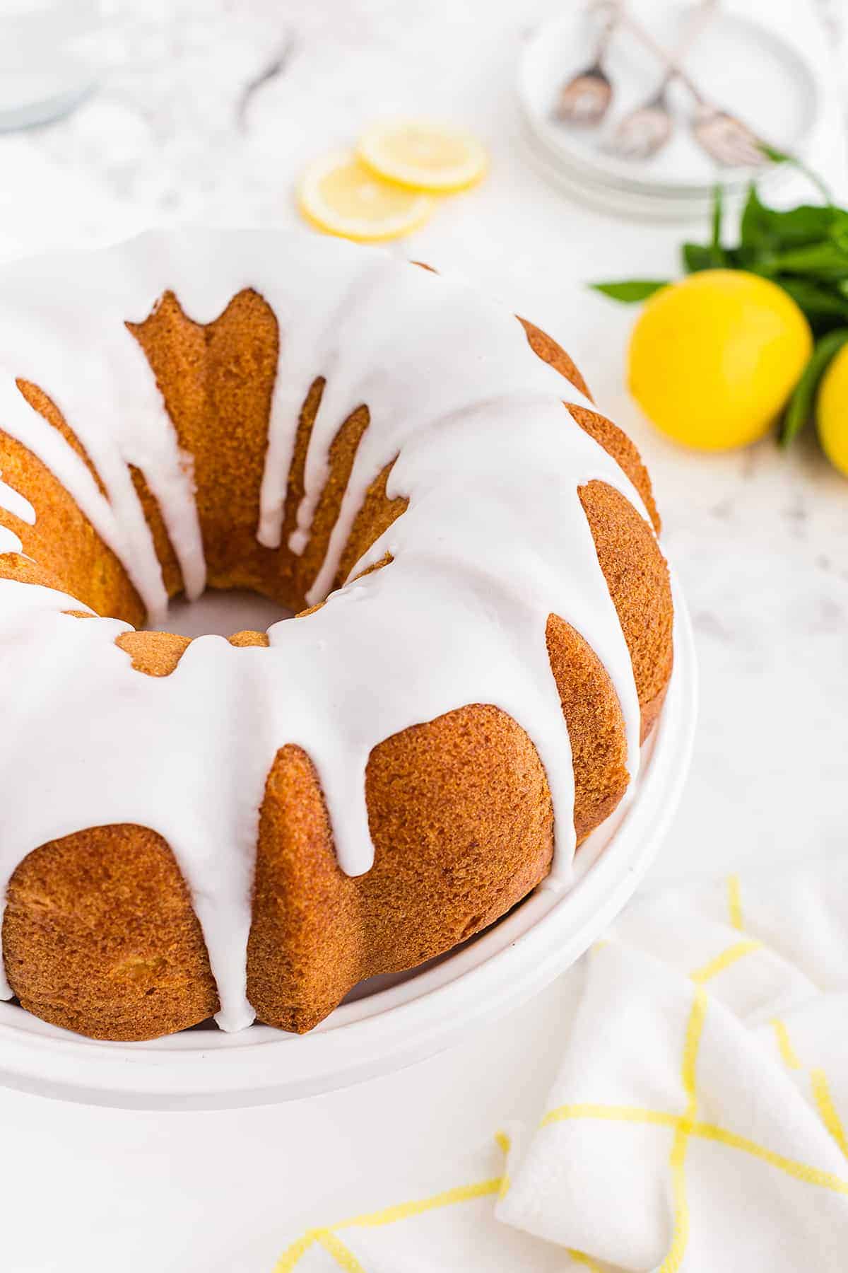 lemon bundt cake recipe on white cake stand.