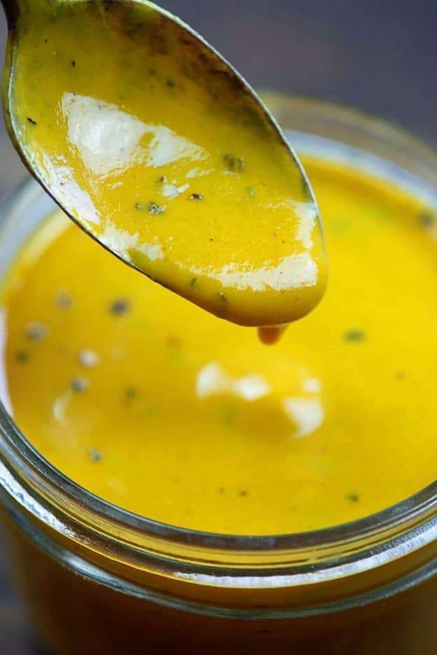 Mustard based BBQ sauce on spoon over jar.