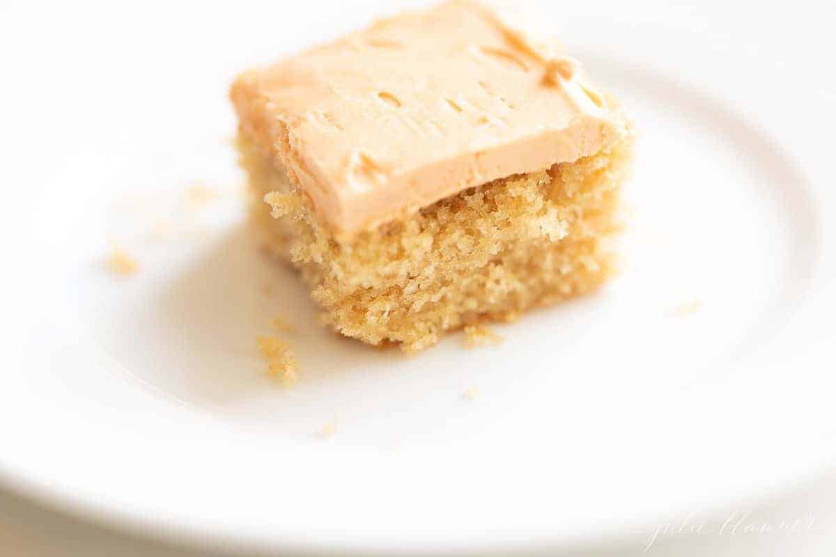 A close up view of a square slice of butterscotch cake on a white plate.