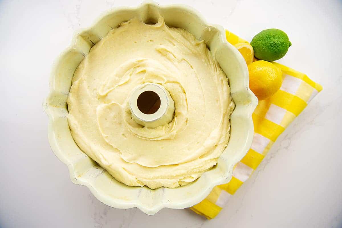 7 up cake batter in bundt pan next to lemon and limes.