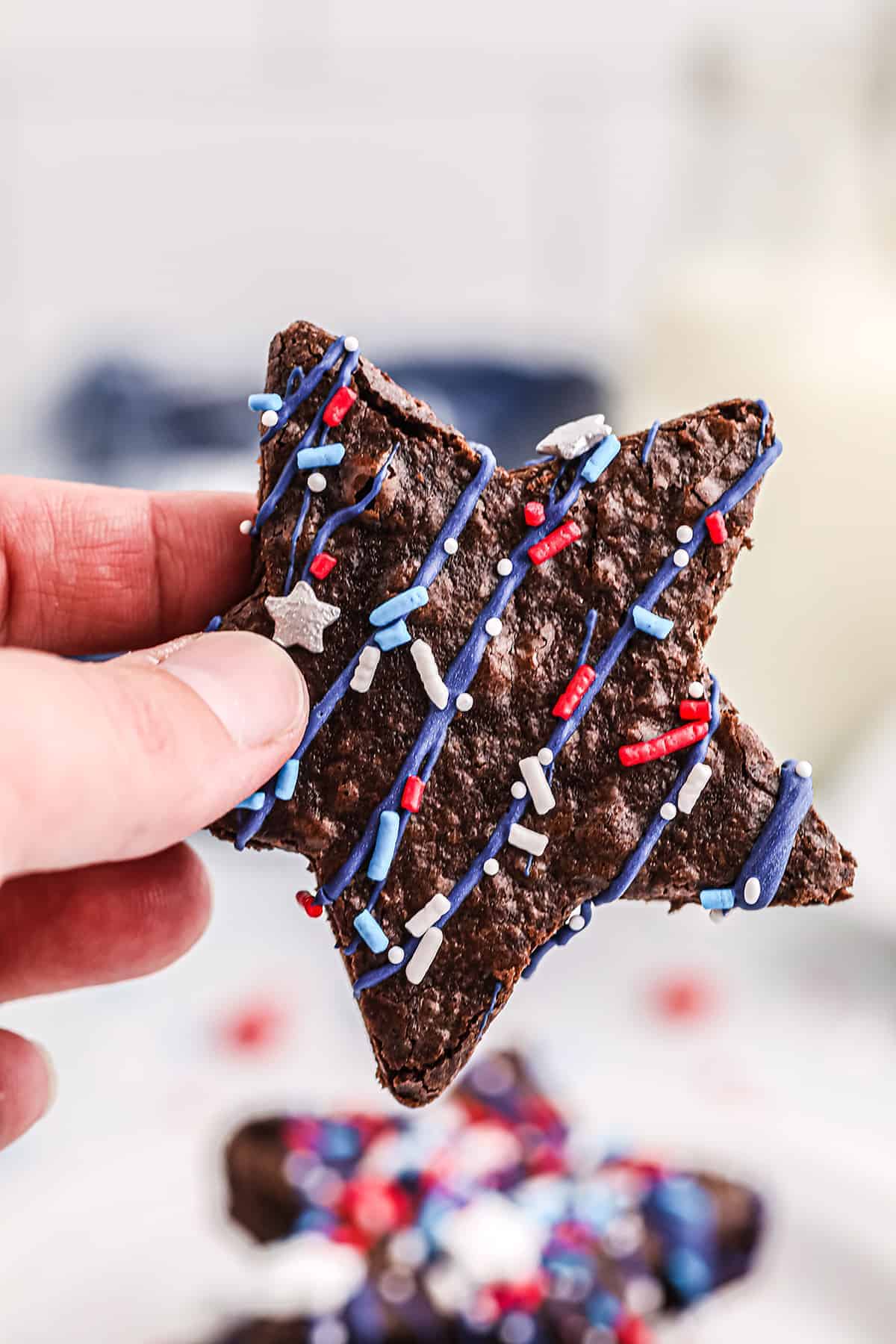 woman holding a star shaped brownie decorated for the Fourth of July.