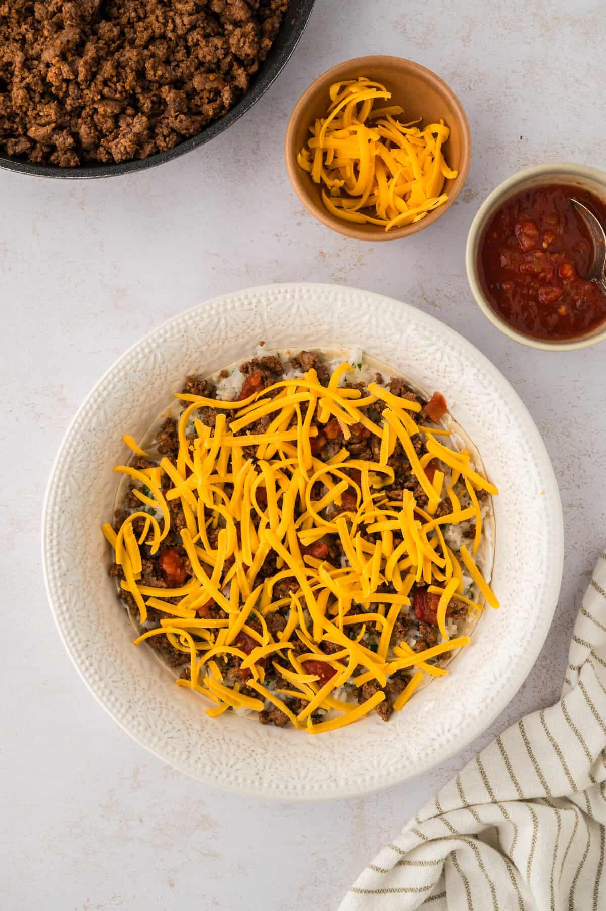 Burrito casserole being layered in pie plate.