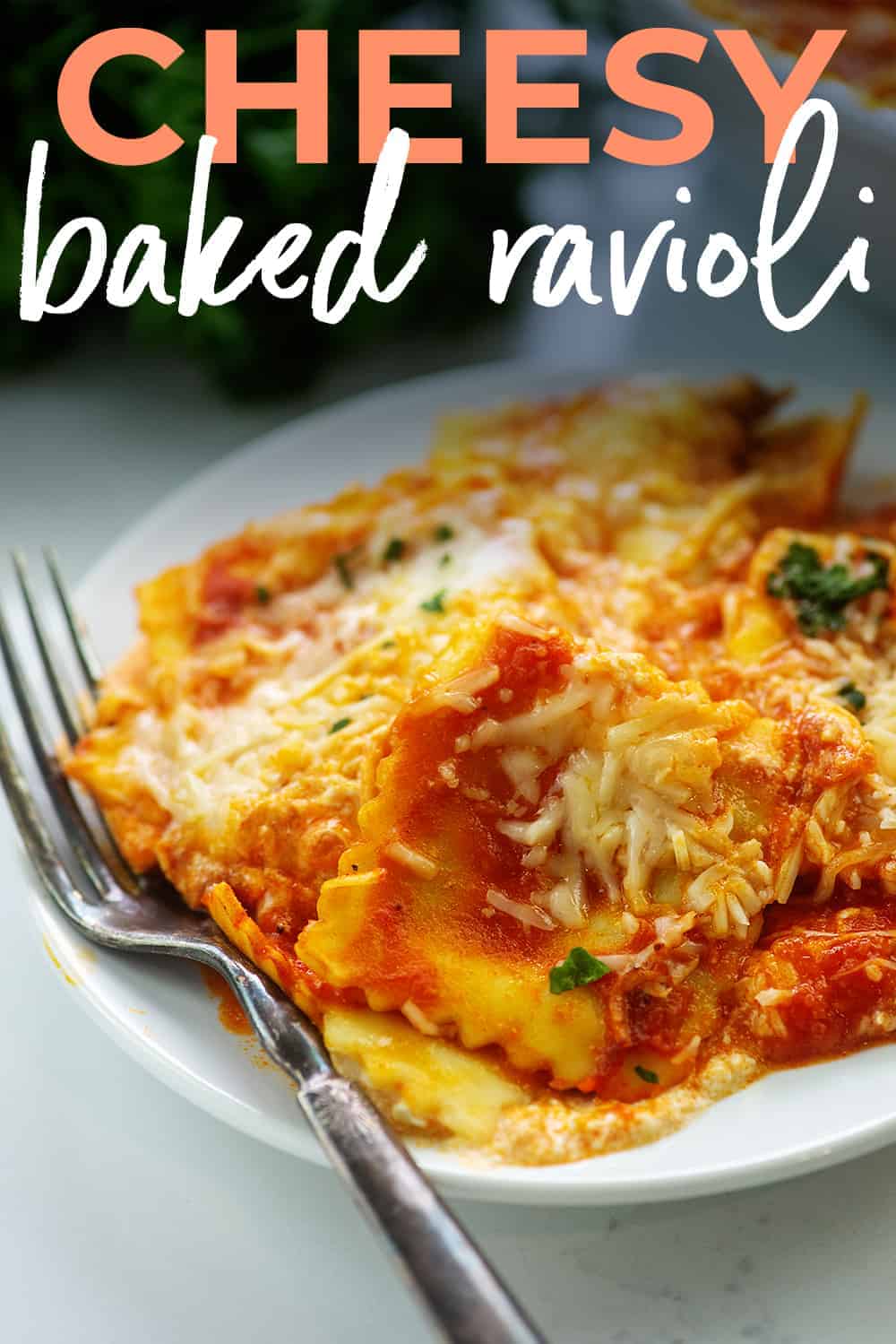 cheesy baked ravioli on white plate with text for Pinterest.