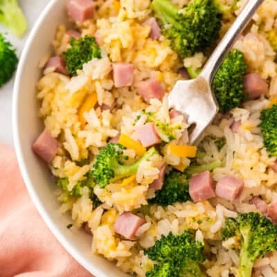 Dish full of cheesy broccoli rice mixed with ham.
