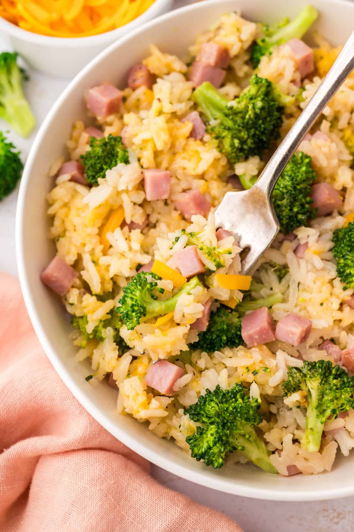 Dish full of cheesy broccoli rice mixed with ham.