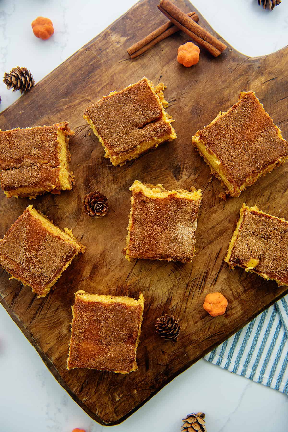 pumpkin cheesecake bars on wooden board.