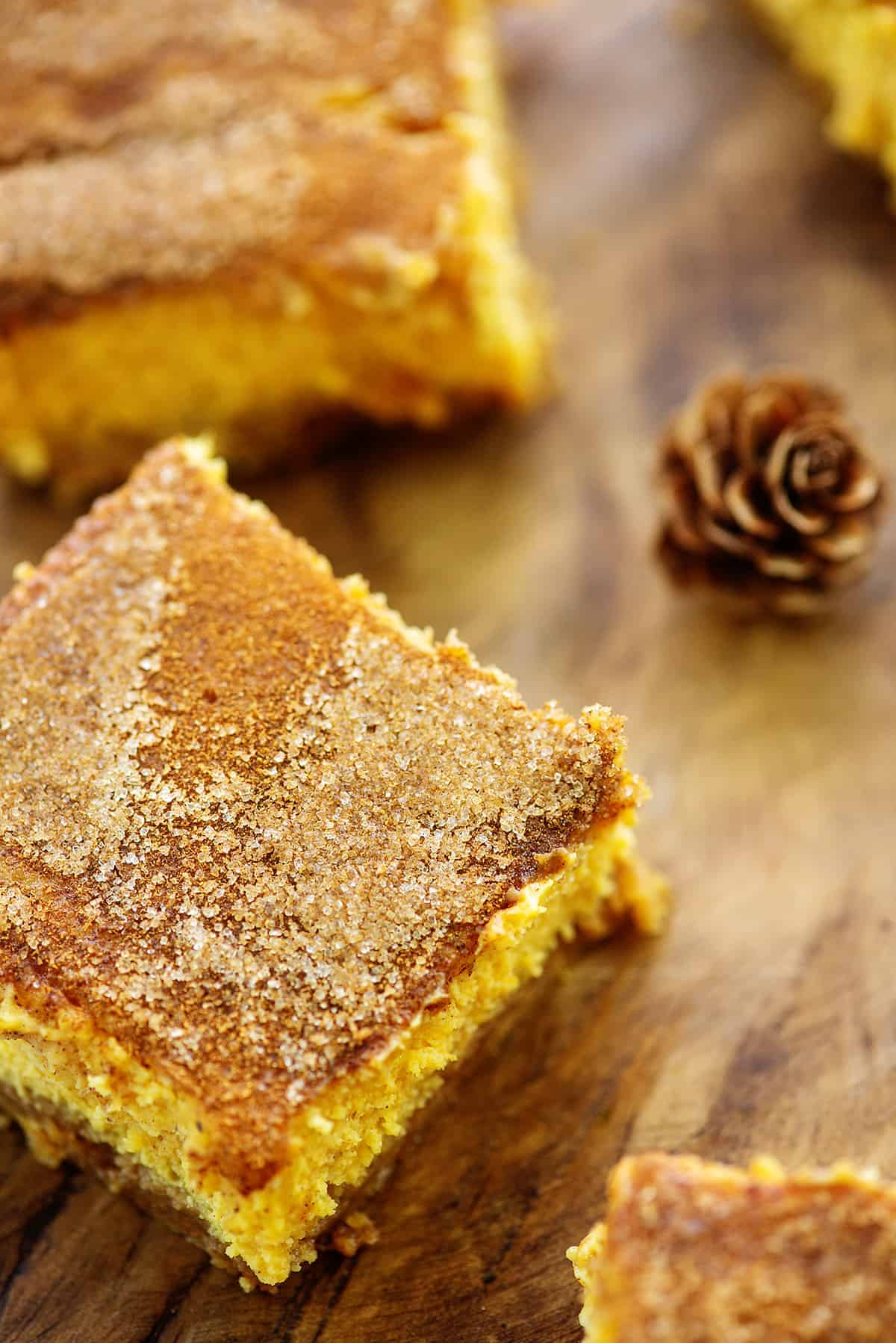 snickerdoodle pumpkin cheesecake bars on wooden cutting board.