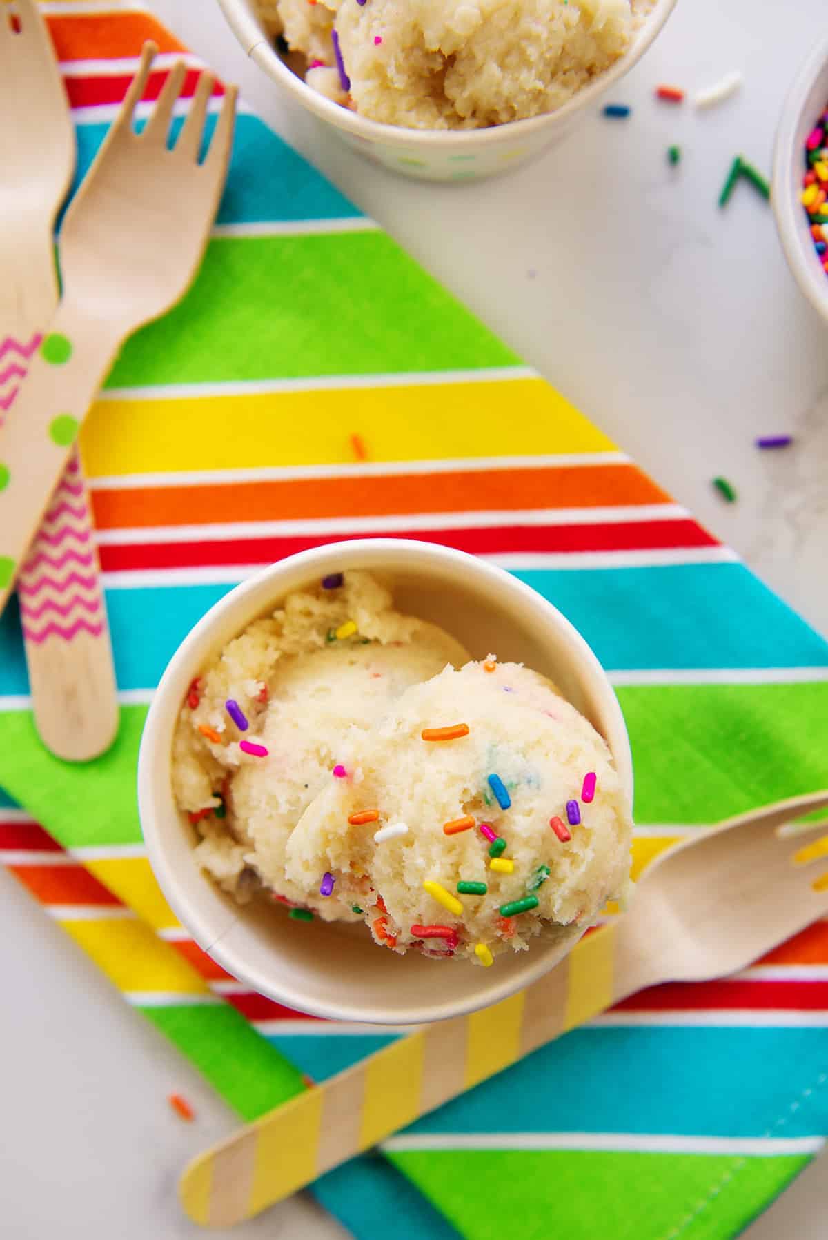 edible sugar cookie dough in small cup on striped napkin.