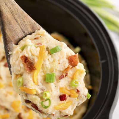 Loaded mashed potatoes on wooden spoon.