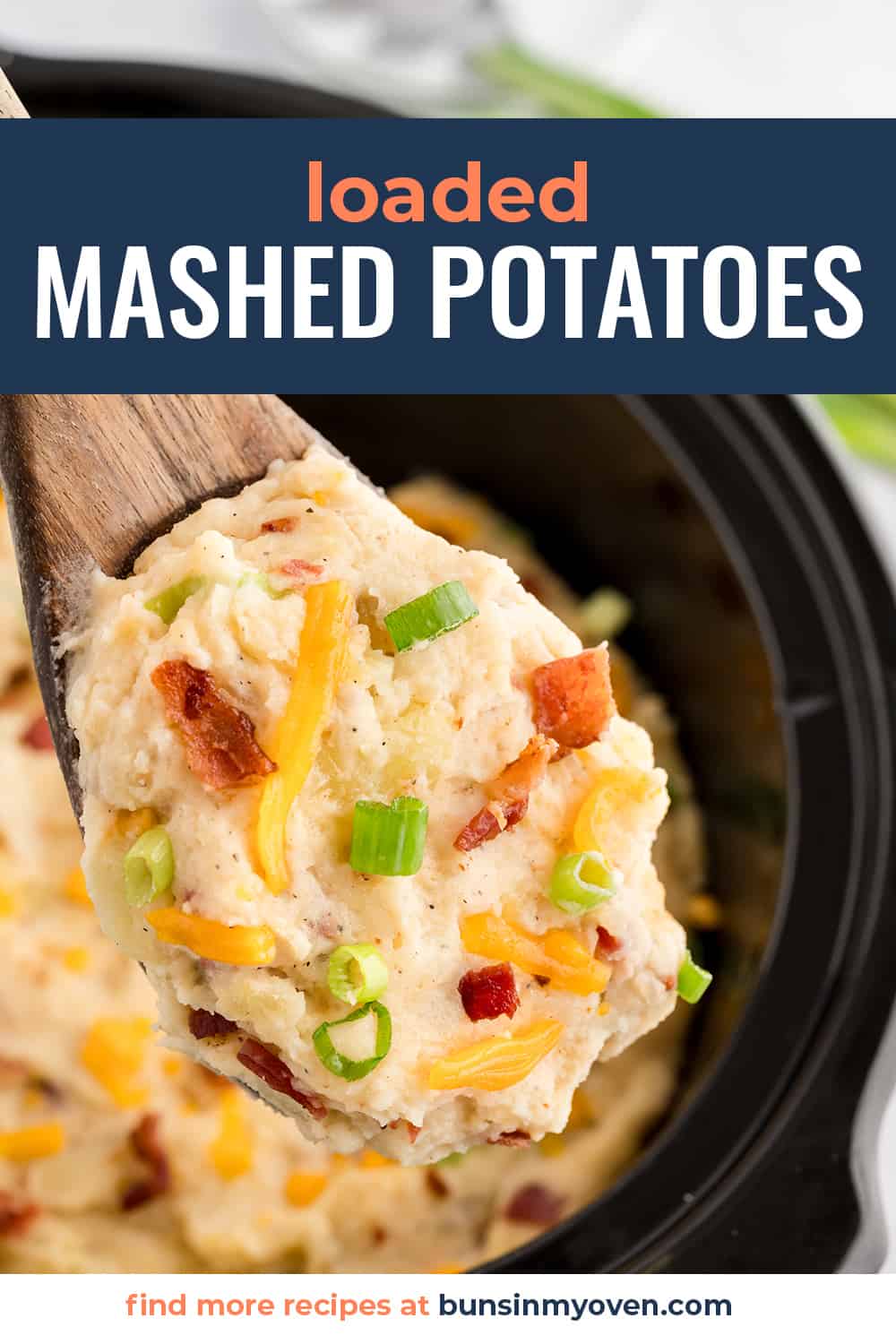 Loaded mashed potatoes on wooden spoon in crockpot.