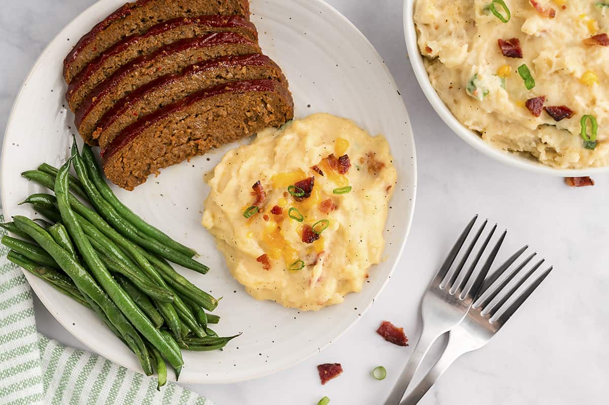 Plate topped with mashed potatoes, meatloaf, and green beans.