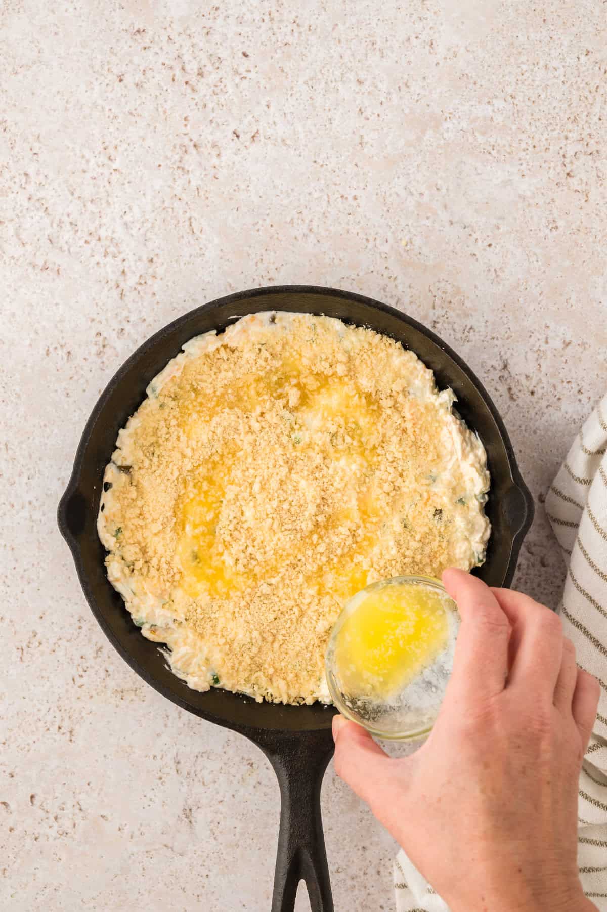 Panko and butter on top of jalapeno cheese dip in cast iron skillet before baking.