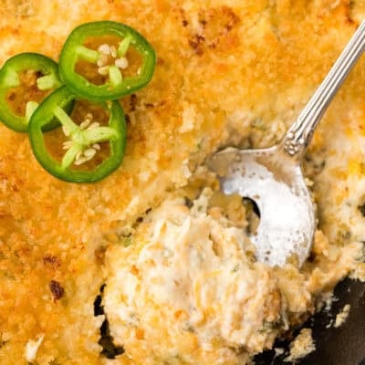 Jalapeno popper dip in cast iron skillet with spoon.