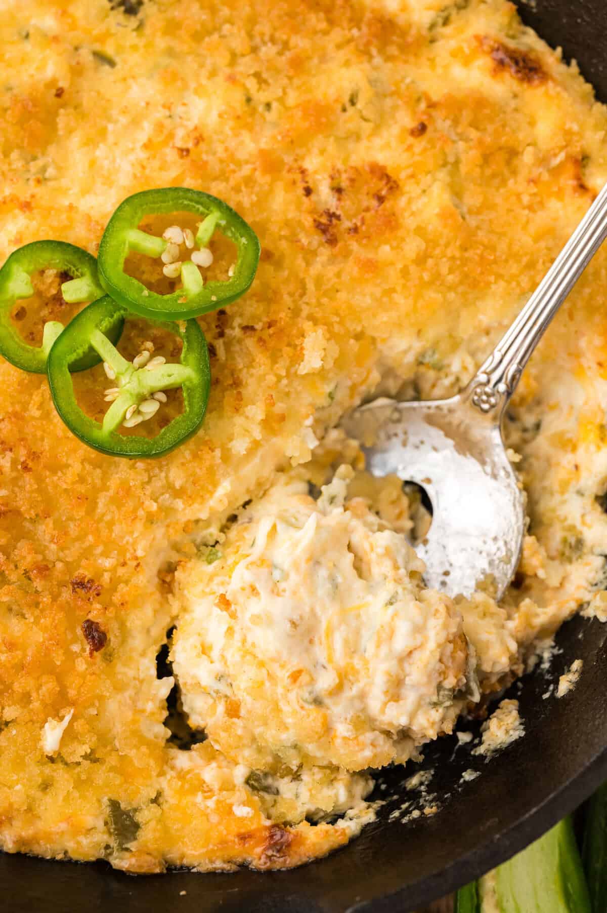 Jalapeno popper dip in cast iron skillet with spoon.