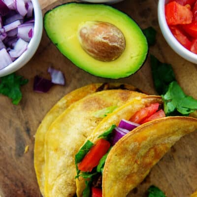 fried air fryer tacos on wooden board.