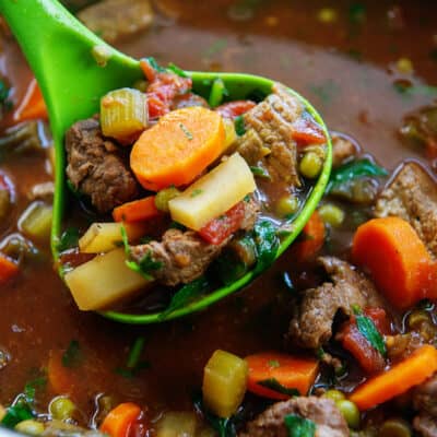crockpot vegetable beef soup in a ladle.