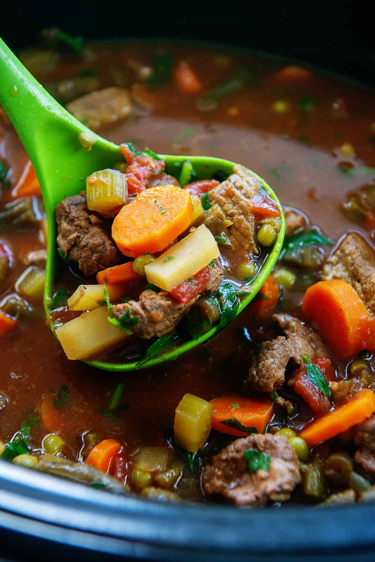 crockpot vegetable beef soup in a ladle.