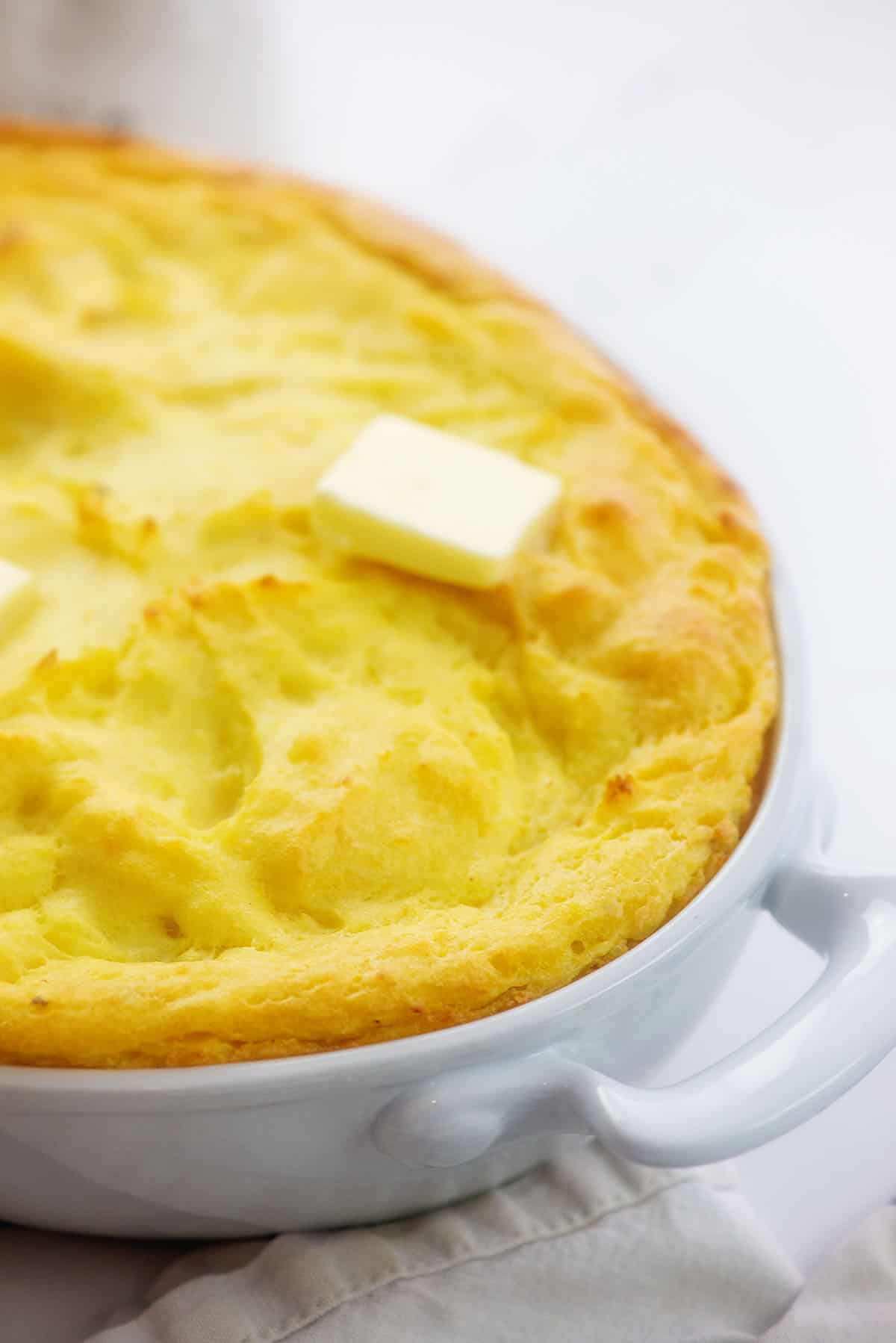 puffy baked potatoes in white dish.